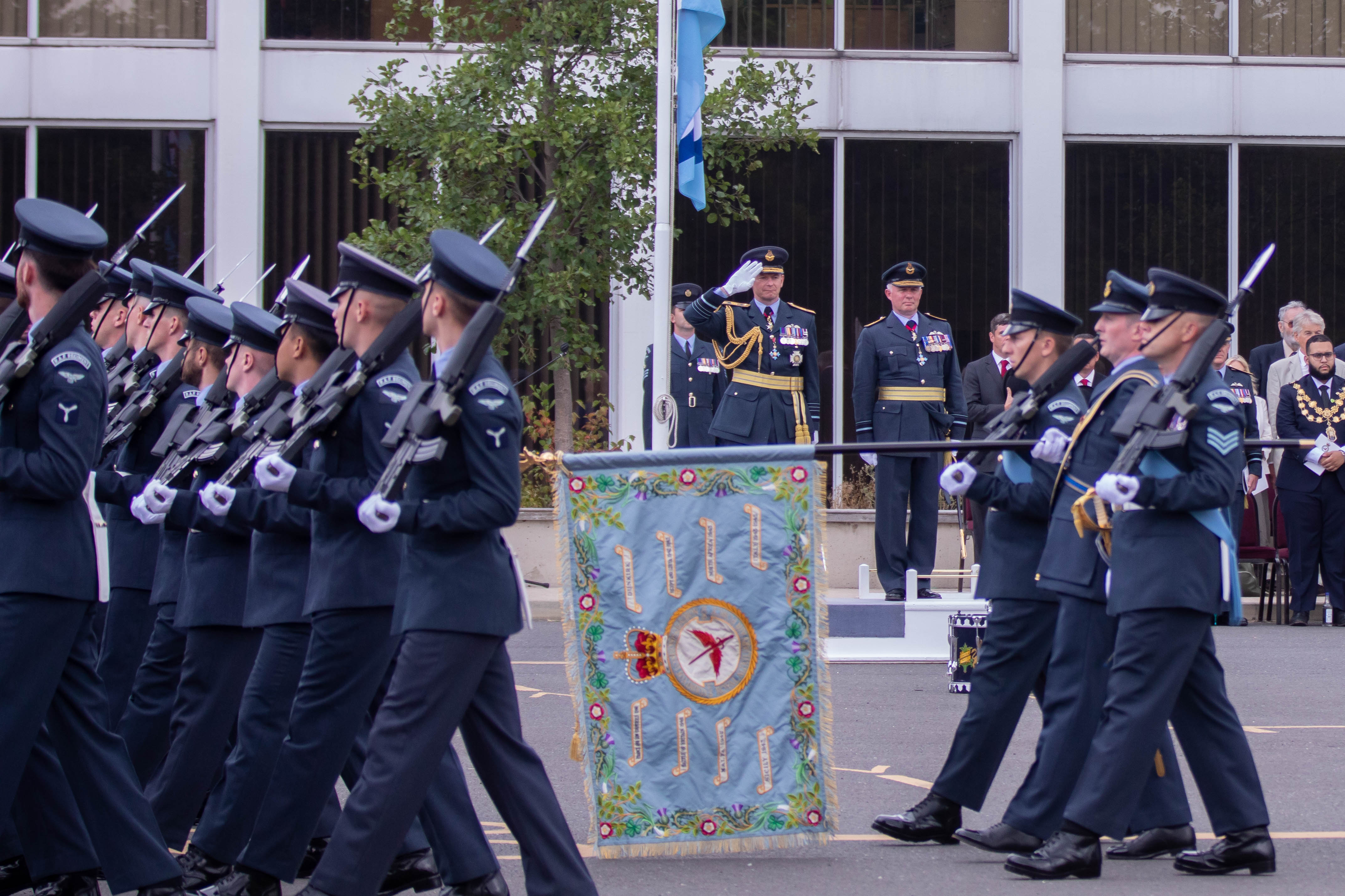 Image shows Squadron parading with rifles and carrying standard, as Chief of the Air Staff salutes behind.